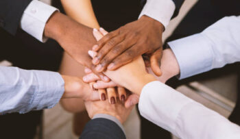 Business unity. Multiethnic corporate teame stacking hands together in office, close up